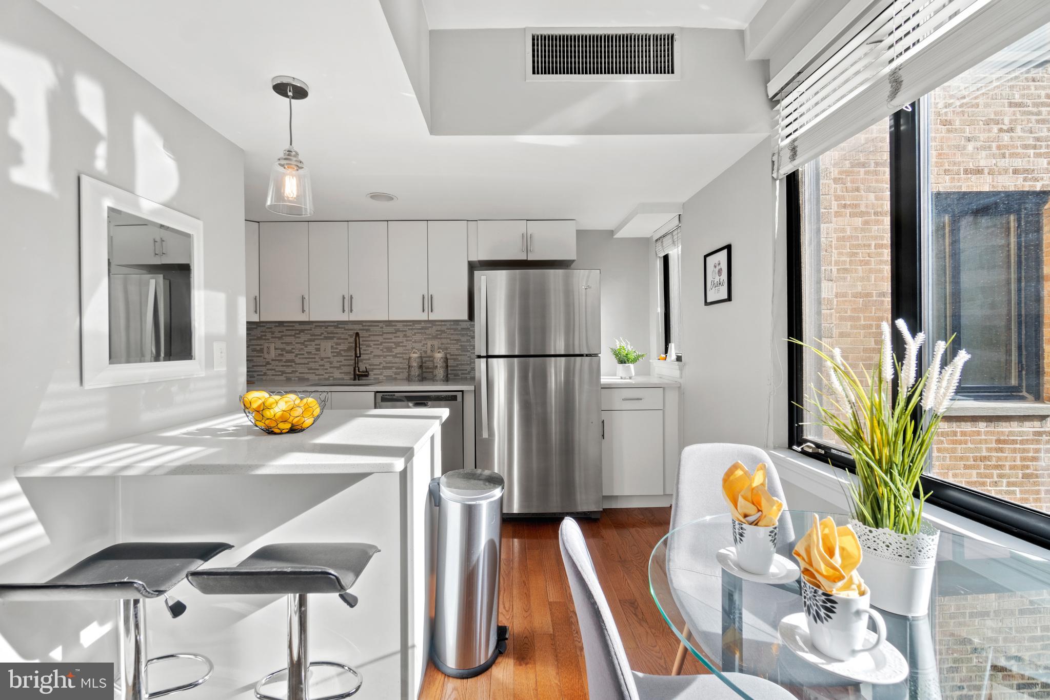 1701 16th Street Northwest, Unit 421 Washington, DC 20009 - Photo 8 of 20 a kitchen with stainless steel appliances a refrigerator a sink a dining table and chairs