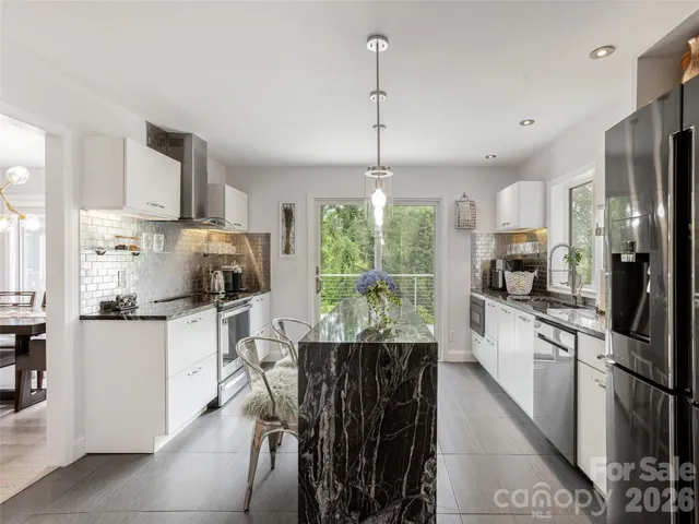 a kitchen with stainless steel appliances kitchen island granite countertop a refrigerator a stove a sink a dining table and chairs with wooden floor