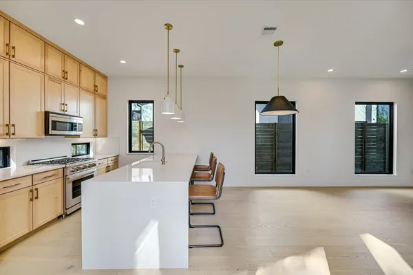 a kitchen with stainless steel appliances granite countertop a refrigerator a stove and a sink with wooden floor