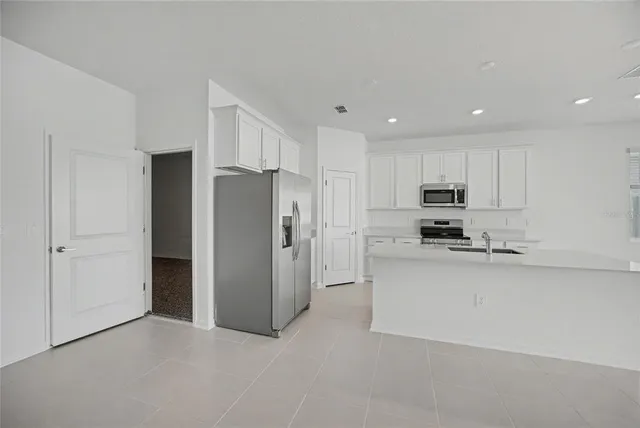 a view of kitchen with kitchen island white cabinets and stainless steel appliances