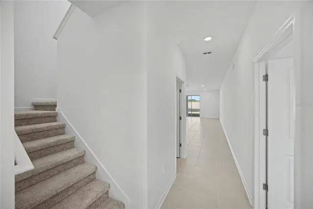 a view of a hallway with wooden floor and a bathroom