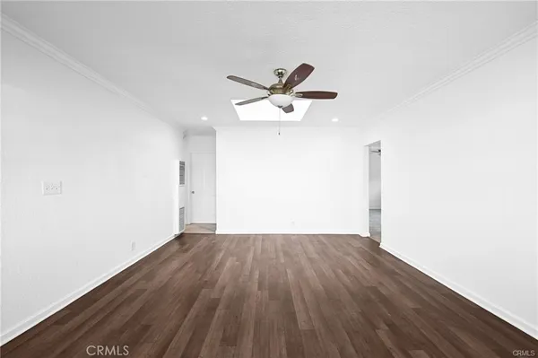 an empty room with wooden floor and a ceiling fan