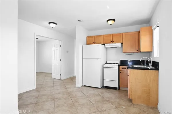 a kitchen with a refrigerator a stove top oven and cabinets