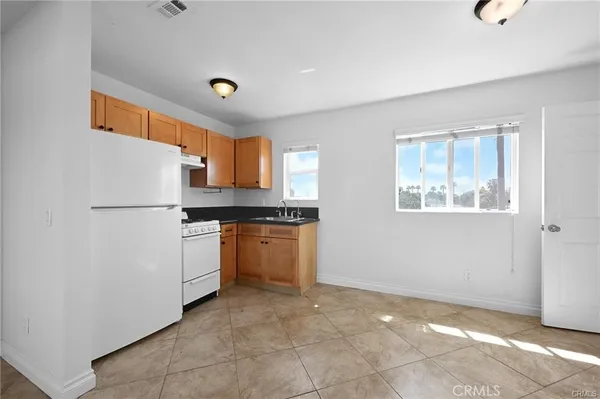 a kitchen with granite countertop a refrigerator and a stove top oven