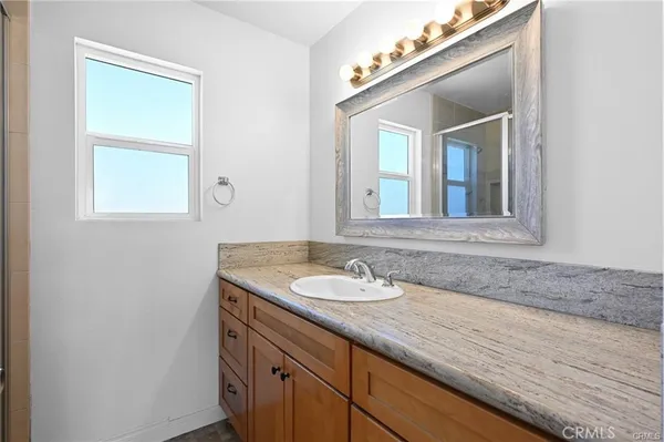 a bathroom with a granite countertop sink and a mirror