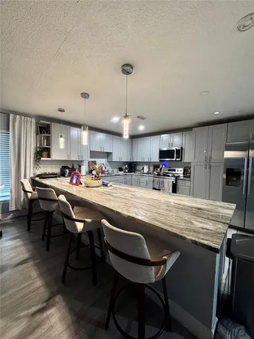 a kitchen with stainless steel appliances granite countertop a sink a stove and chairs