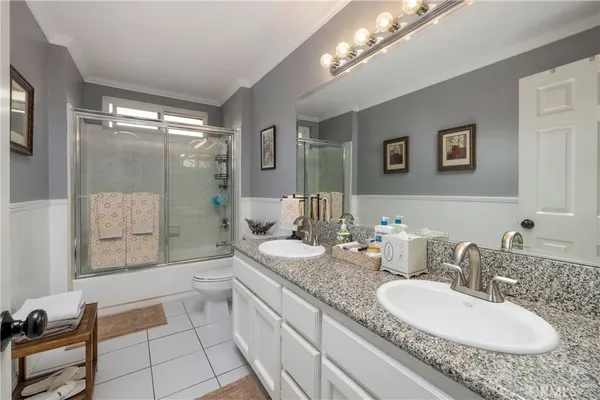a bathroom with a granite countertop double vanity sink a mirror and a shower