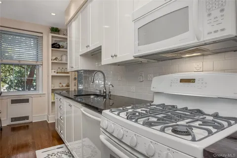 a kitchen with granite countertop stainless steel appliances stove a sink dishwasher and cabinets with wooden floor