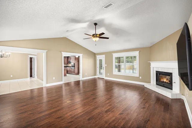 a view of an empty room with window and wooden floor