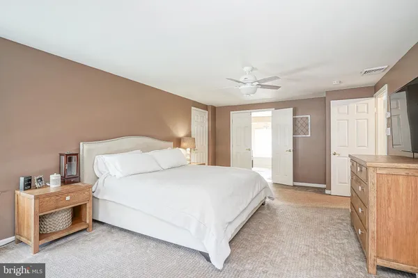 a bedroom with a large bed a flat tv screen and a dresser