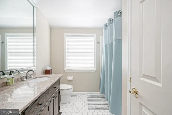 a bathroom with a granite countertop double vanity sink a mirror and a window