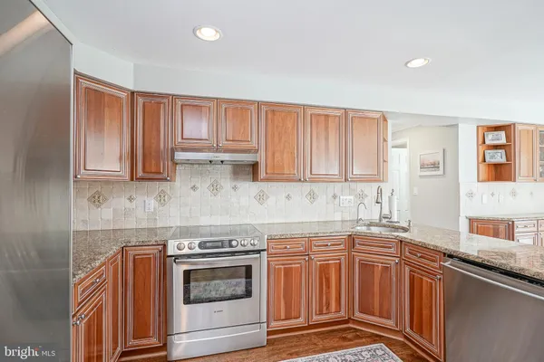 a kitchen with stainless steel appliances granite countertop a sink stove and cabinets