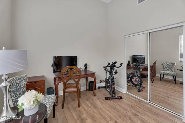 a view of a white house with a large tree and wooden fence