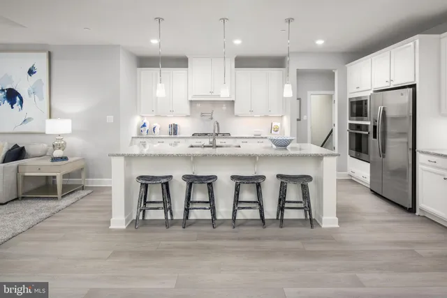 a kitchen with stainless steel appliances granite countertop a table chairs sink refrigerator and microwave