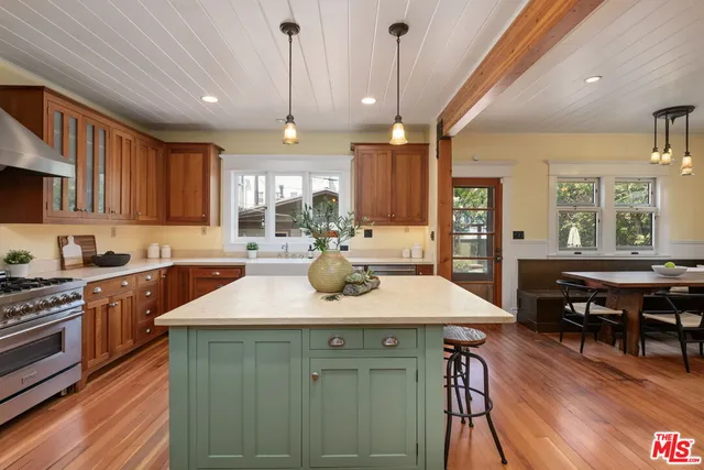 a kitchen with stainless steel appliances granite countertop a stove a refrigerator a dining table and chairs with wooden floor