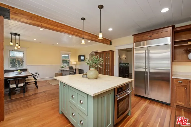 a kitchen with stainless steel appliances kitchen island granite countertop a table chairs sink and cabinets