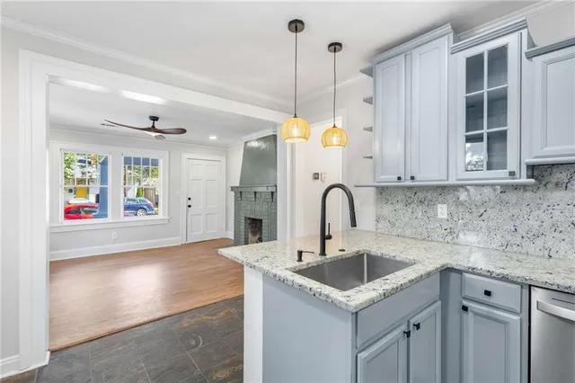 a kitchen that has a sink a microwave oven a stove and white cabinets with wooden floor