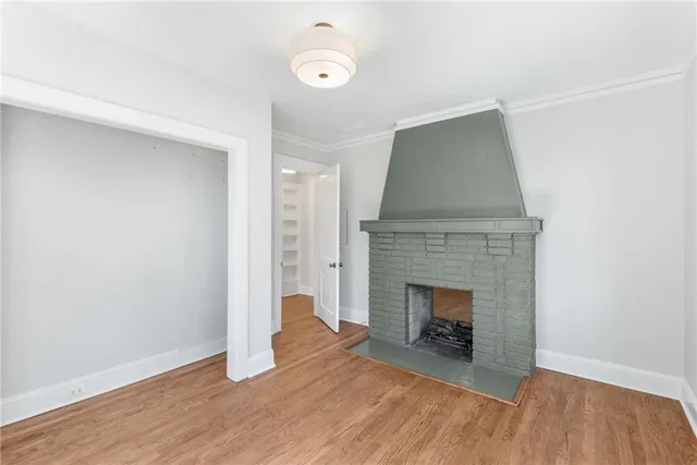 a view of an empty room with wooden floor and fireplace