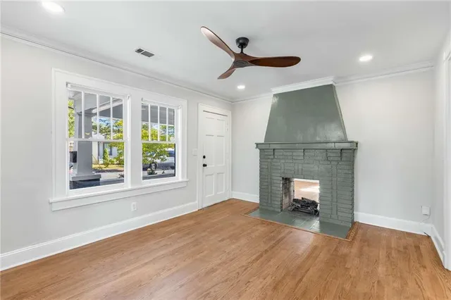 a view of an empty room with wooden floor fireplace and a window