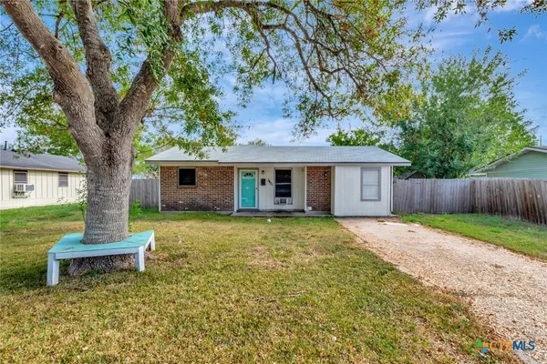 a backyard of a house with table and chairs plants and large tree