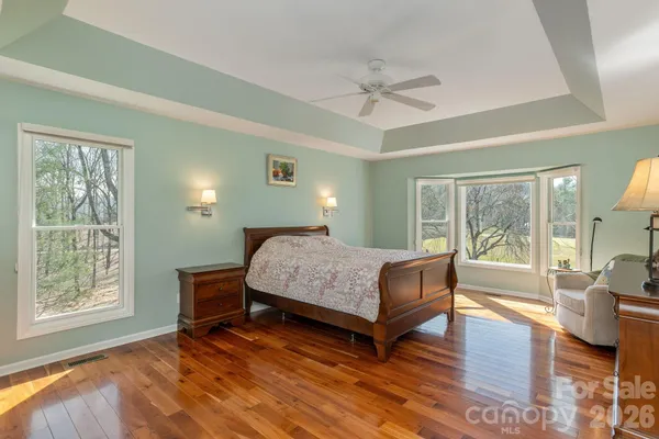 a bedroom with a large window and a wooden floor