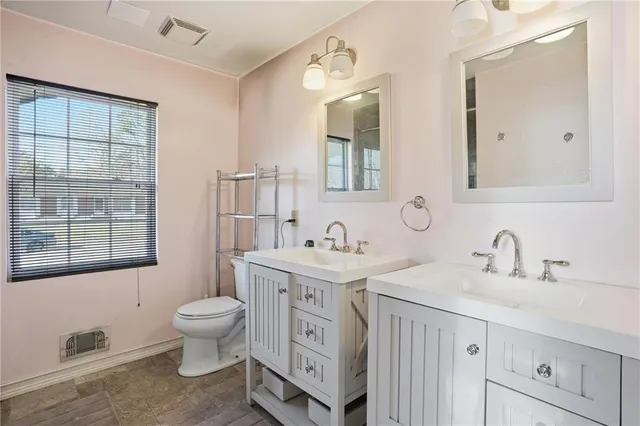 a spacious bathroom with a double vanity sink a mirror and a toilet