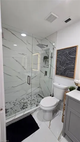 a bathroom with a granite countertop toilet a sink and a mirror