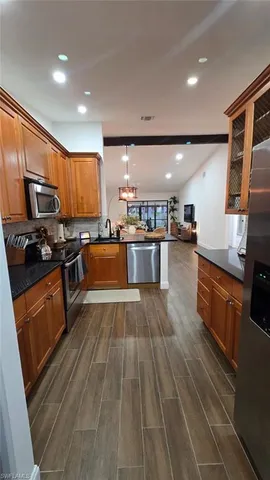 a kitchen with stainless steel appliances wooden floors wooden cabinets and granite counter tops