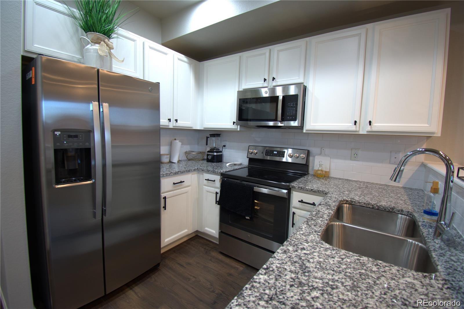 6435 North Dunkirk Street Denver, CO 80249 - Photo 6 of 12 a kitchen with stainless steel appliances granite countertop a refrigerator a stove a sink and a microwave