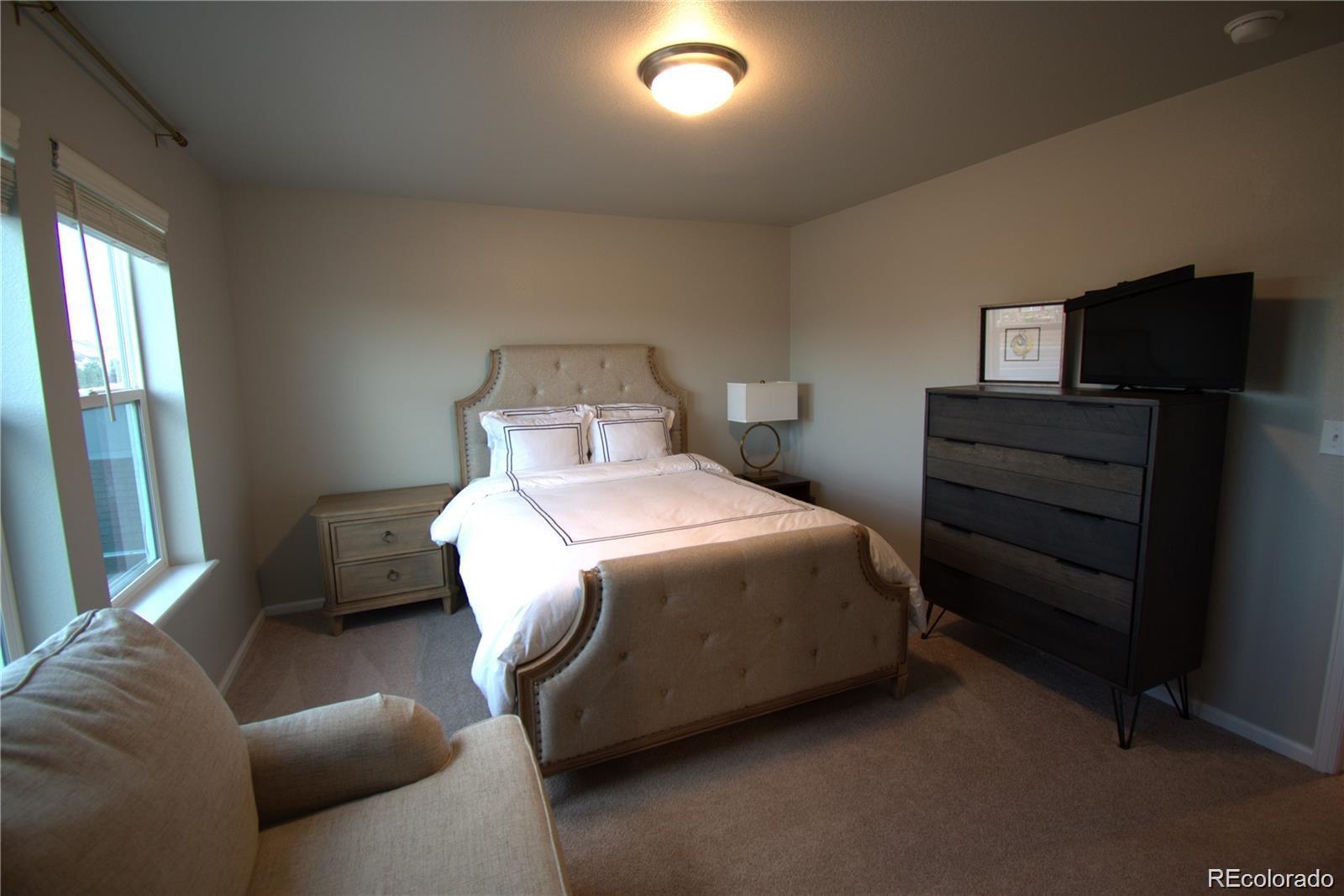 6435 North Dunkirk Street Denver, CO 80249 - Photo 8 of 12 a bedroom with a bed and a television