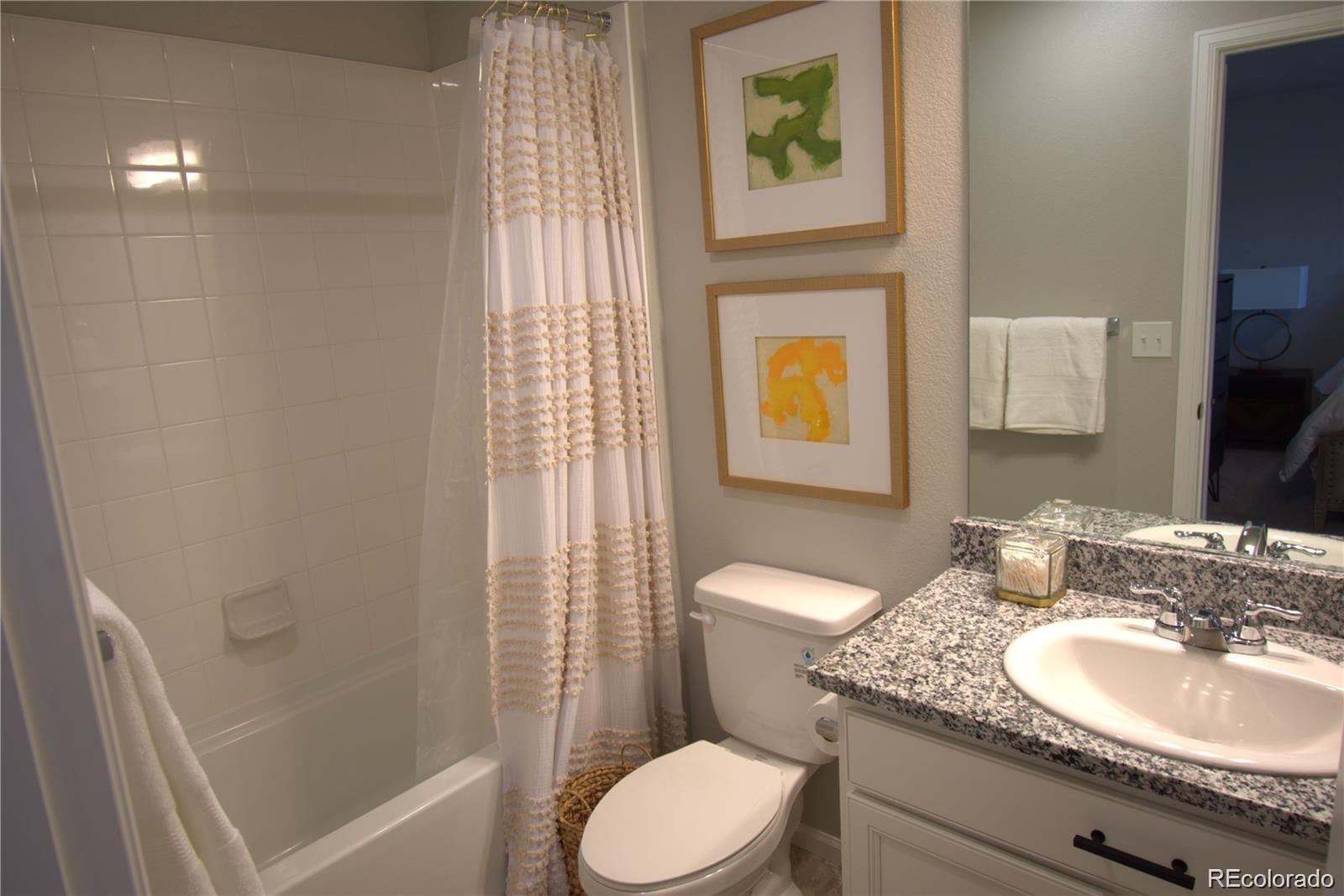 6435 North Dunkirk Street Denver, CO 80249 - Photo 9 of 12 a bathroom with a granite countertop sink toilet and shower