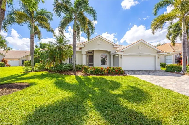 a front view of a house with a yard and palm trees