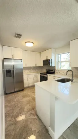 a kitchen with stainless steel appliances granite countertop a refrigerator a stove a sink and a microwave