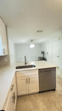 a view of a kitchen with sink and white cabinets