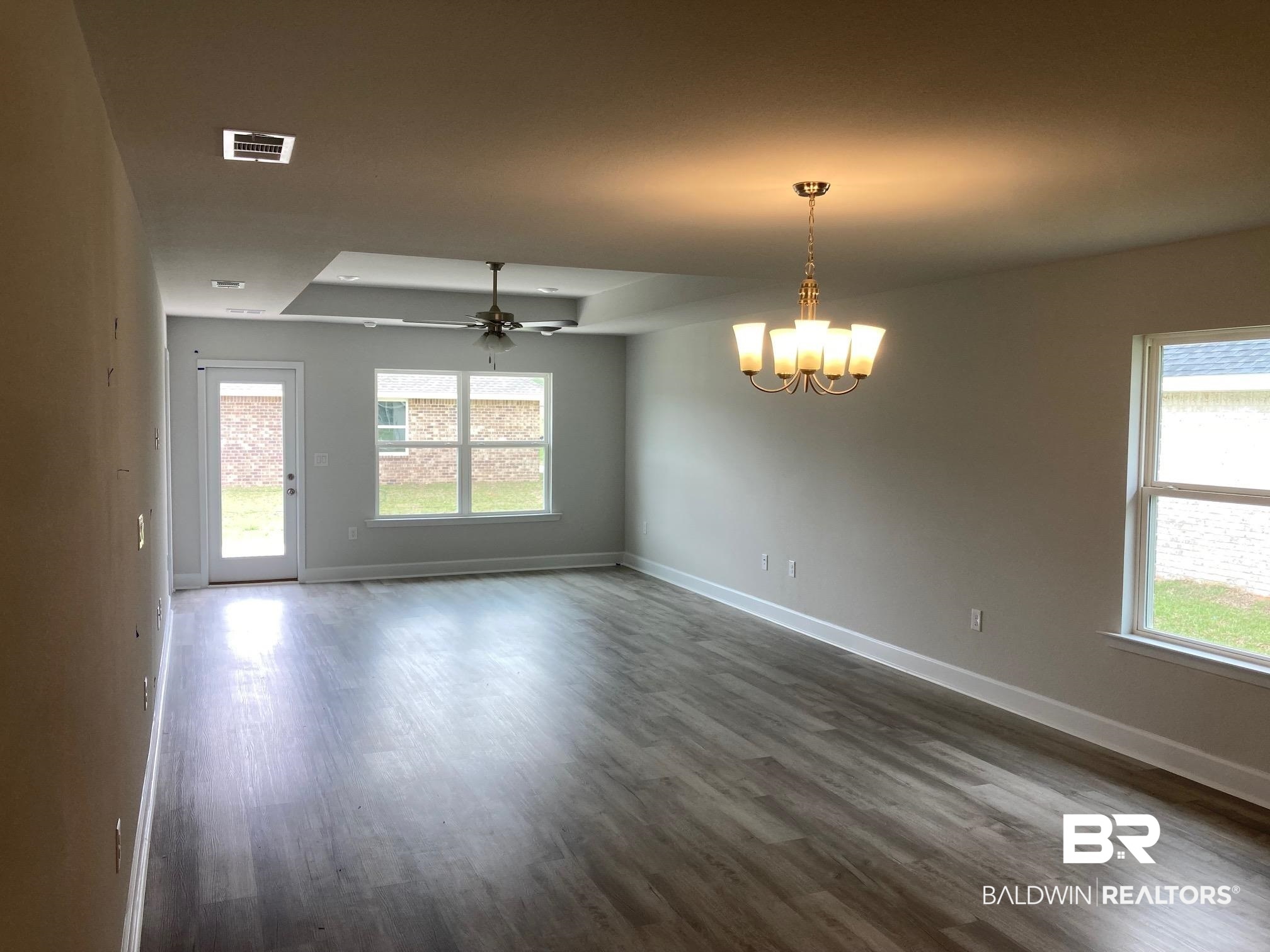 705 Mayflower Drive Foley, AL 36535 - Photo 7 of 19 Spare room with dark wood finished floors, ceiling fan with notable chandelier, baseboards, and visible vents