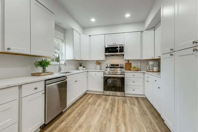 a kitchen with kitchen island granite countertop white cabinets a sink and dishwasher with wooden floor