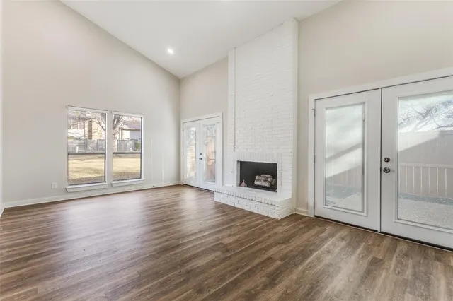 an empty room with wooden floor fireplace and windows