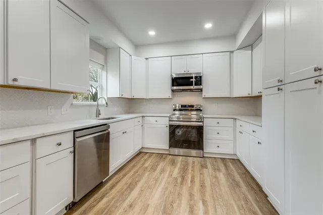 a kitchen with kitchen island granite countertop white cabinets and stainless steel appliances