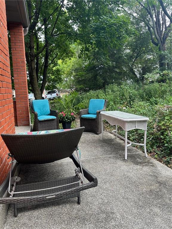 341 Kramer Way Pittsburgh, PA 15211 - Photo 6 of 37 Picture a cozy, secluded back porch, measuring 9 feet by 4 feet, seamlessly connecting to a slightly larger patio of 16 feet by 7 feet. This intimate outdoor space, tucked between tall, leafy trees, feels like a hidden retreat—a modern-day tree fort where you can escape the world without leaving home. The rich red brick walls of the house surround the area, creating a warm and inviting backdrop.