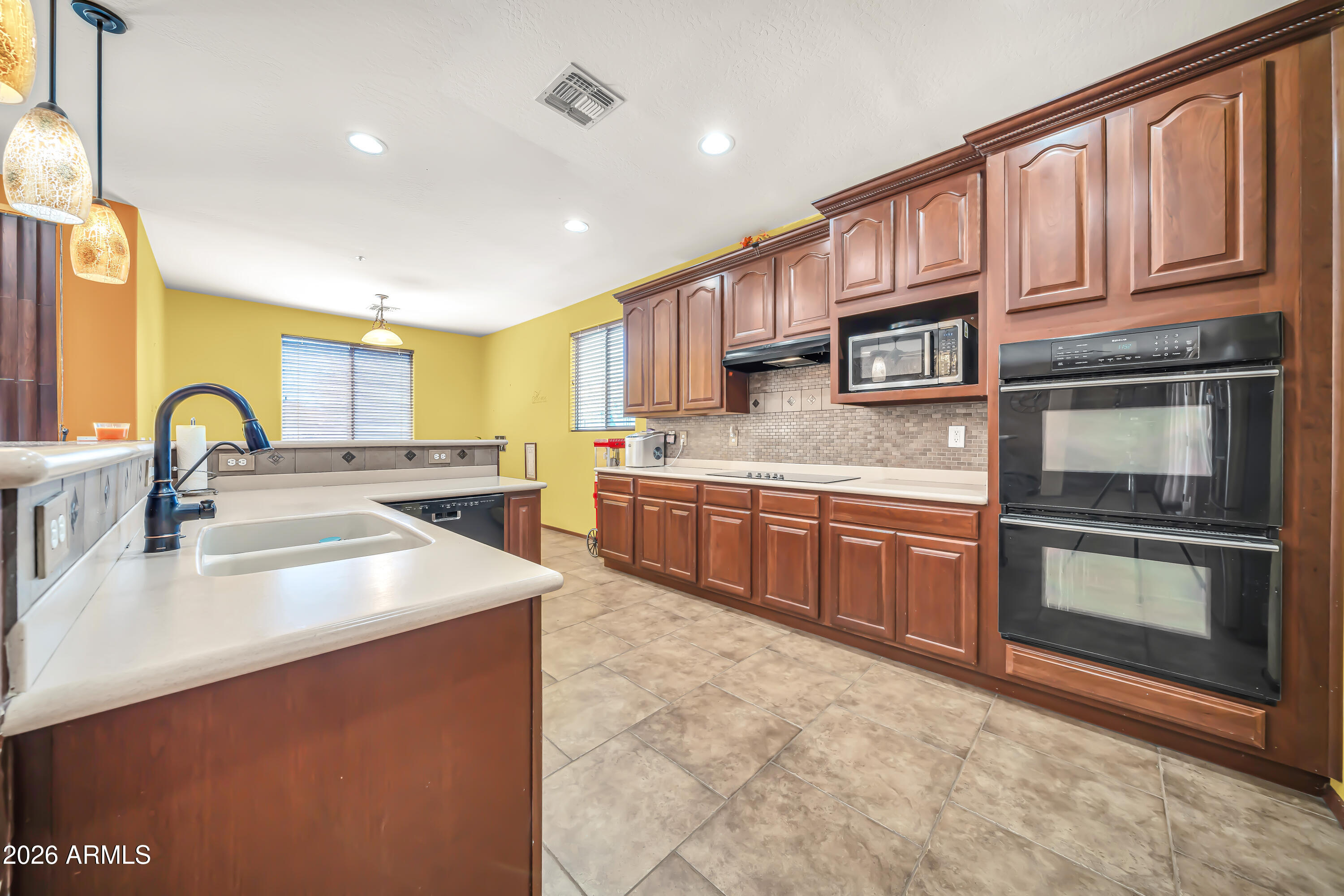 15327 West Roma Avenue Goodyear, AZ 85395 - Photo 21 of 65 a kitchen with stainless steel appliances granite countertop a stove a sink and a microwave