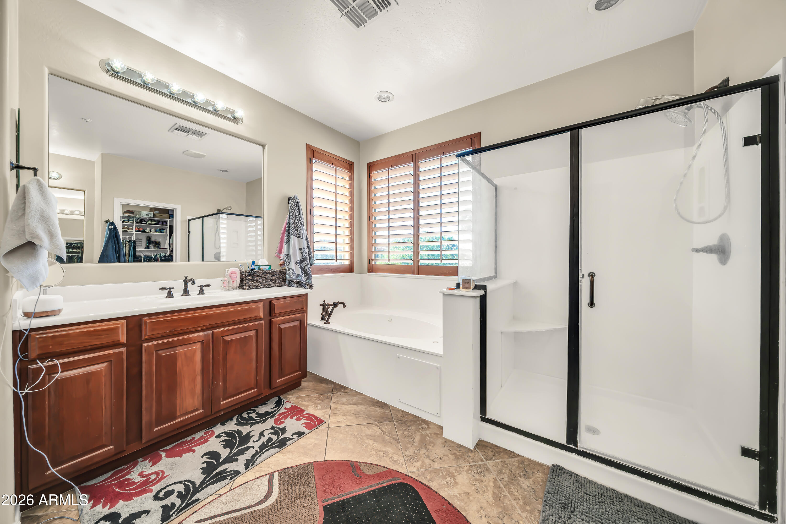 15327 West Roma Avenue Goodyear, AZ 85395 - Photo 27 of 65 a spacious bathroom with a double vanity sink a mirror a bathtub and shower