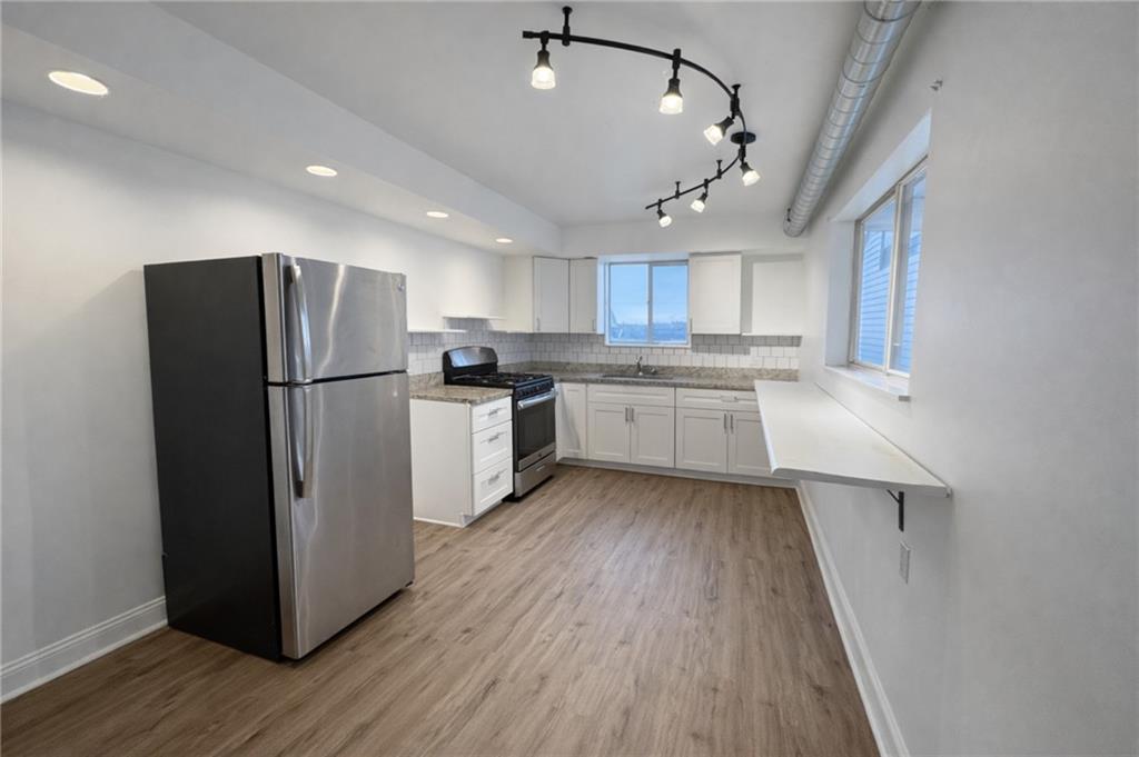 1921 Shamokin Street Pittsburgh, PA 15203 - Photo 4 of 10 a kitchen with stainless steel appliances granite countertop a refrigerator a sink dishwasher a stove and white countertops with wooden floor