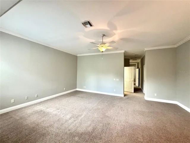 an empty room with a chandelier fan and windows
