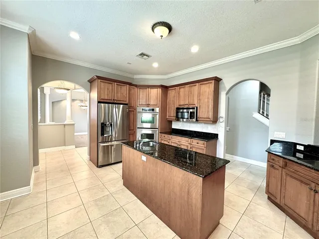 a kitchen with stainless steel appliances granite countertop a refrigerator a stove top oven and sink