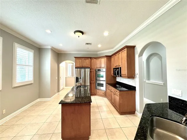 a living room with stainless steel appliances kitchen island granite countertop a refrigerator a stove top oven and a dining table with wooden floor