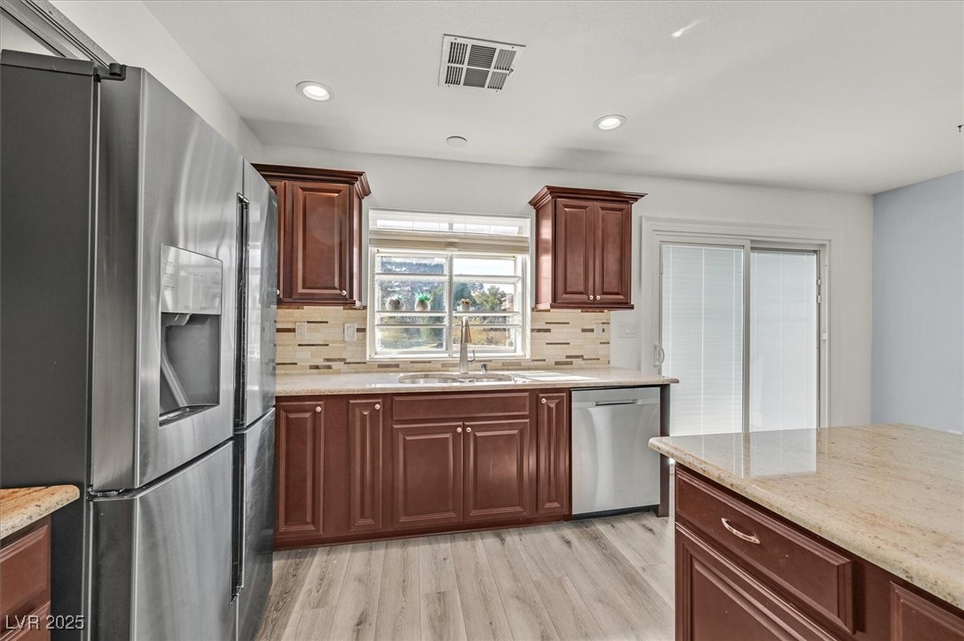 5421 Painted Mirage Road Las Vegas, NV 89149 - Photo 9 of 35 Kitchen featuring visible vents, decorative backsplash, appliances with stainless steel finishes, light wood-style floors, and a sink