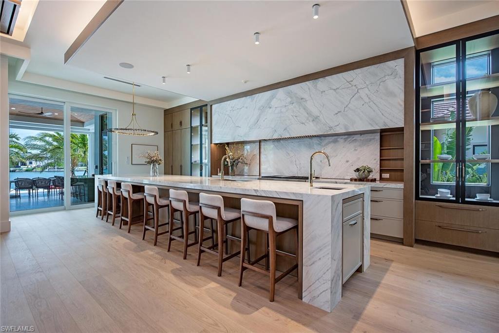 2999 Rum Row Naples, FL 34102 - Photo 13 of 33 Kitchen with light wood-style flooring, a kitchen breakfast bar, a sink, a large island, and modern cabinets