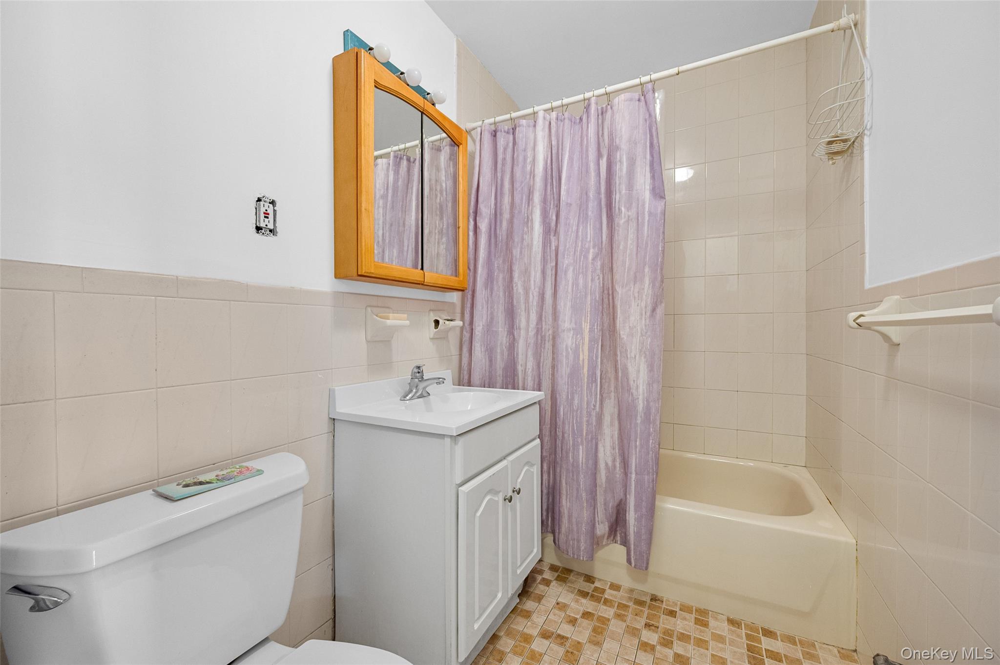 108-10 35th Avenue Queens, NY 11368 - Photo 27 of 29 Bathroom featuring tile walls, vanity, shower / bath combination with curtain, and wainscoting