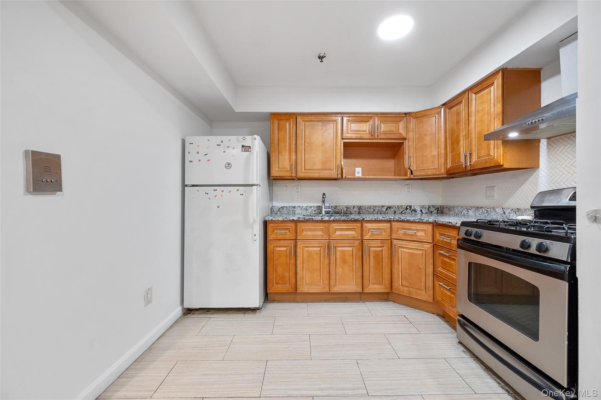 108-10 35th Avenue Queens, NY 11368 - Photo 5 of 29 Kitchen featuring stainless steel gas range oven, freestanding refrigerator, brown cabinets, and wall chimney exhaust hood