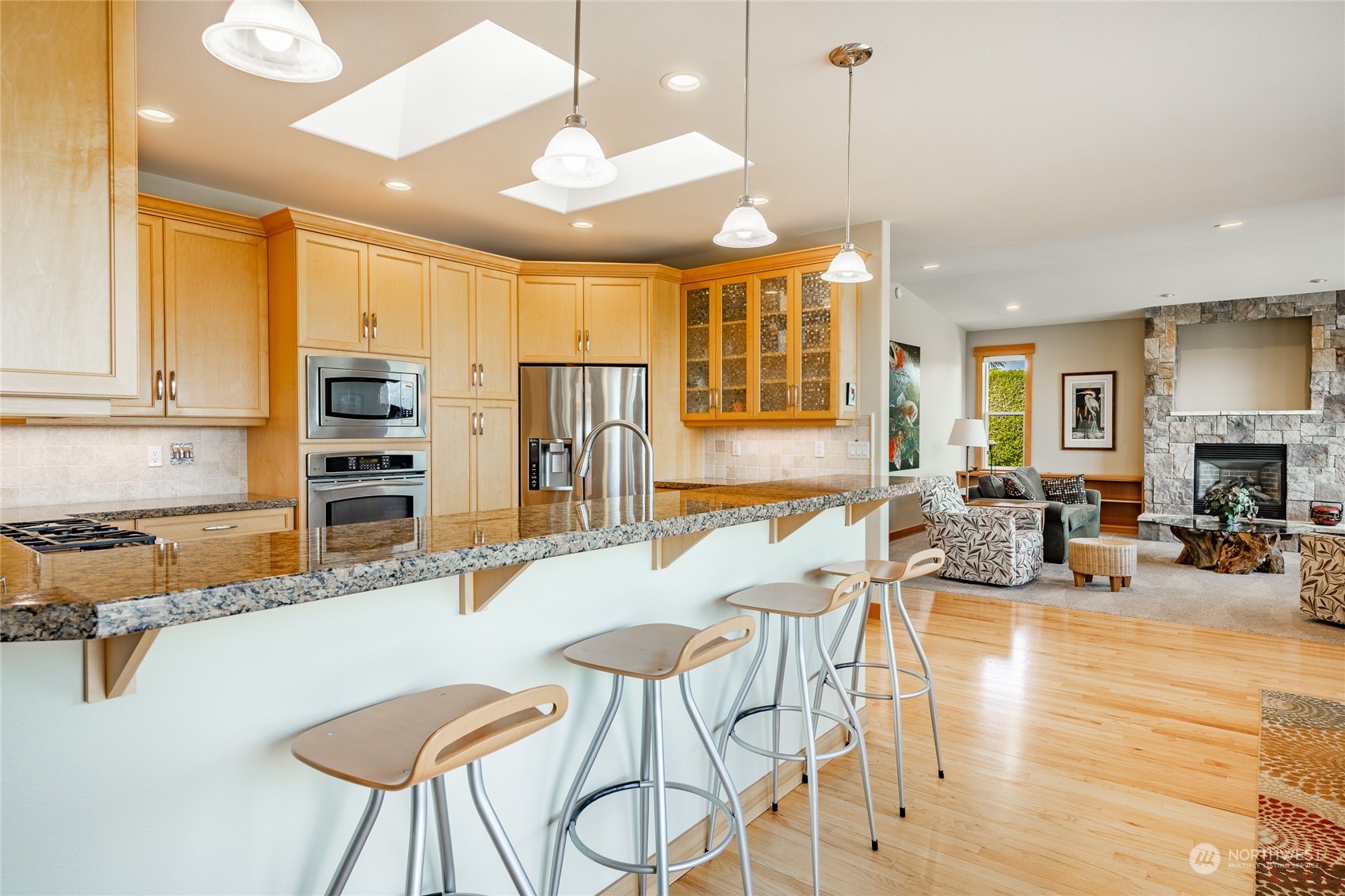 8148 Comox Road Blaine, WA 98230 - Photo 6 of 40 a kitchen with stainless steel appliances granite countertop a stove top oven a sink a dining table and chairs with wooden floor